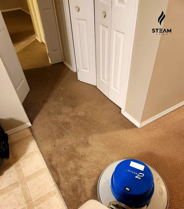 Dirty hallway carpet by closet doors, with cleaning machine