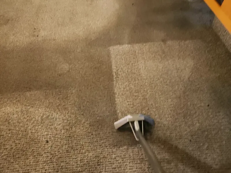 Carpet wand on commercial carpet beside booth seating, showing a cleaned patch next to soiled carpet