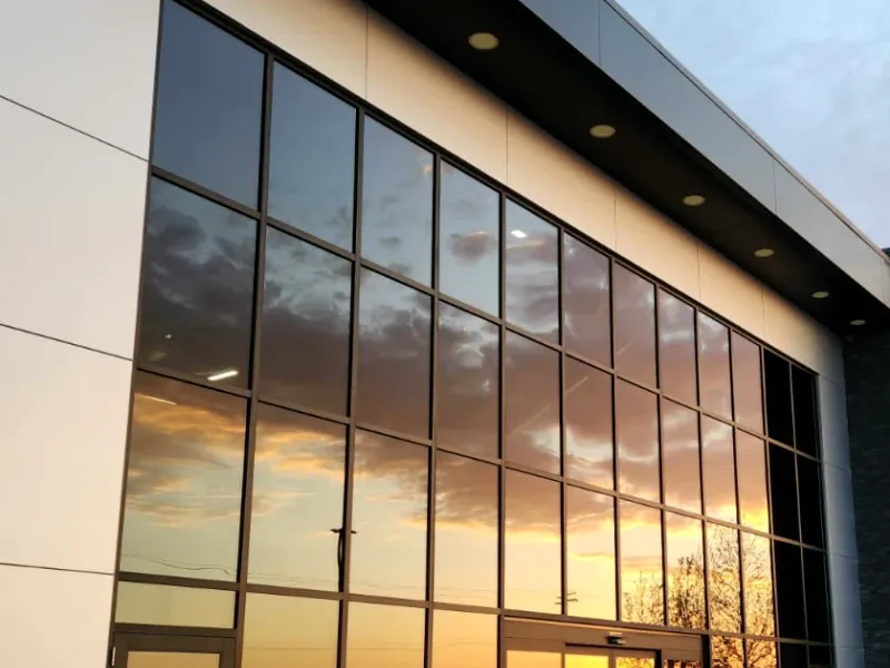 Clean glass front of a commercial building reflecting a sunset