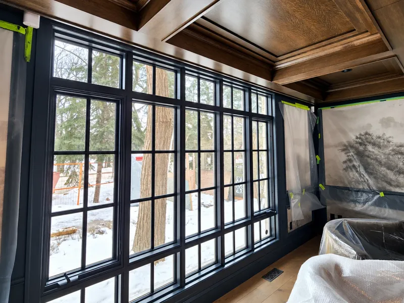 Clean interior windows in a room with the furniture covered for protection